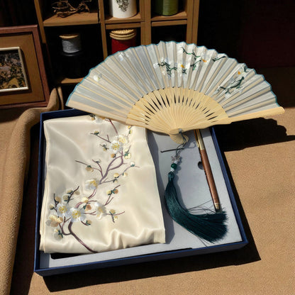 Embroidered fabric with floral design and a folded fan on a box