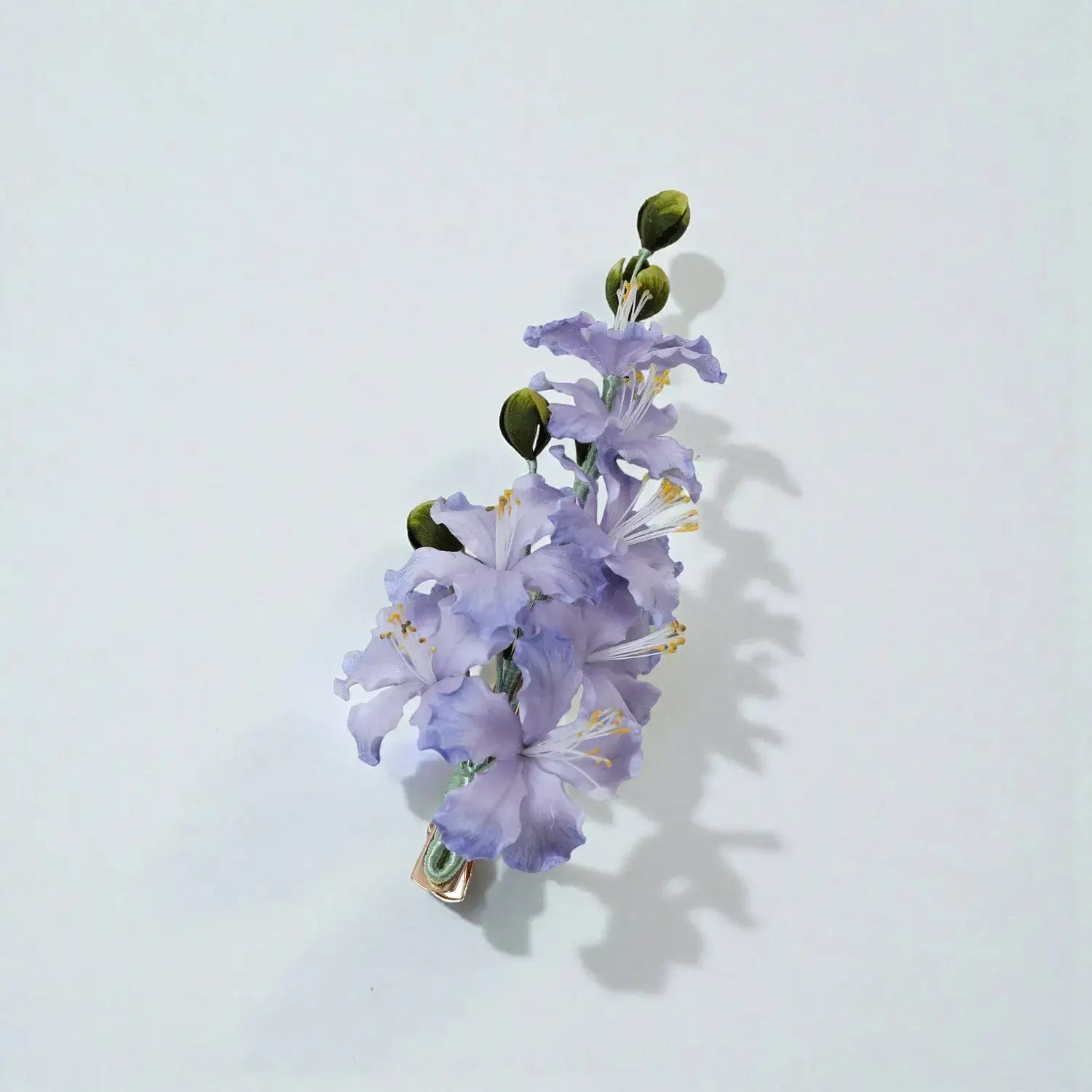 Floral hair clip with purple flowers and green leaves on a light gray background