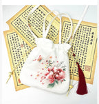 White drawstring bag with floral embroidery on a white background