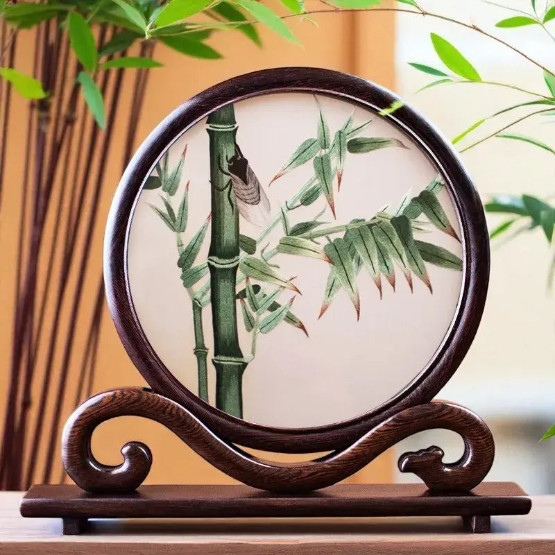 Decorative plate with bamboo design on a wooden stand, surrounded by greenery.