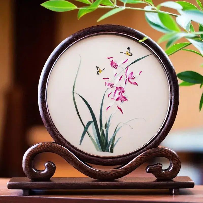 Decorative piece with floral design on a wooden stand, surrounded by green leaves.