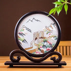 Decorative plate with a mountain and wall design on a wooden stand