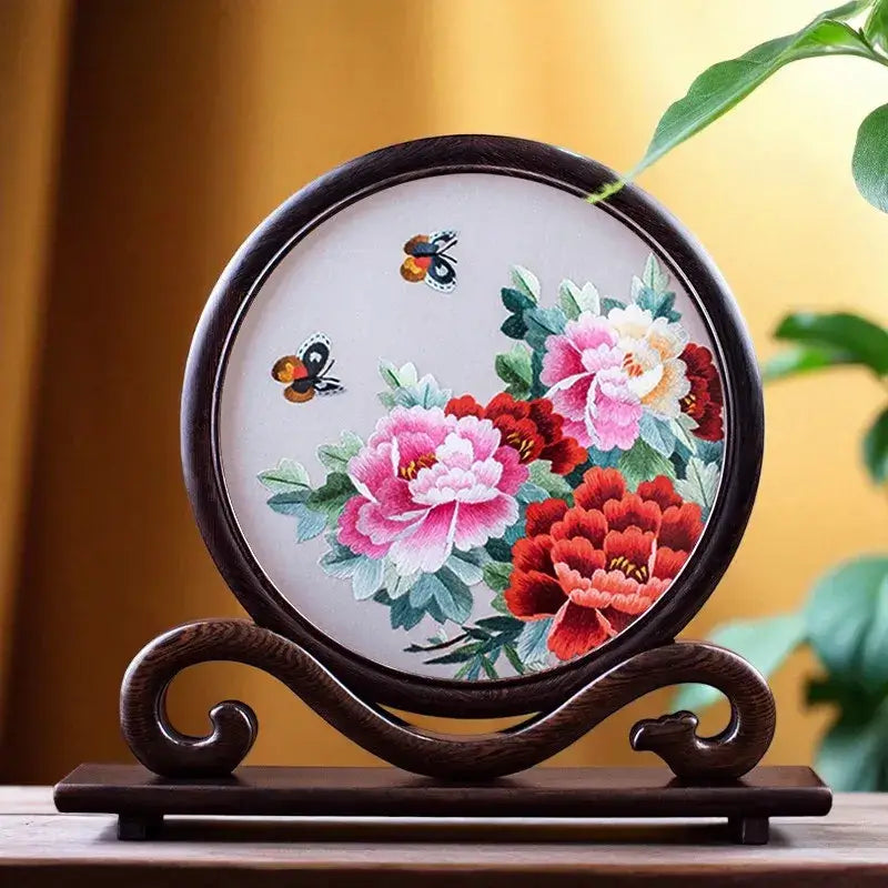 Decorative piece with embroidered flowers and butterflies on a wooden stand.