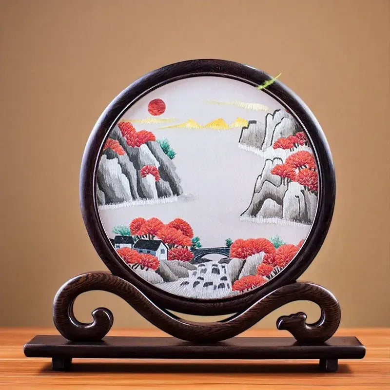Decorative plate with a mountain and tree design on a wooden stand against a brown background