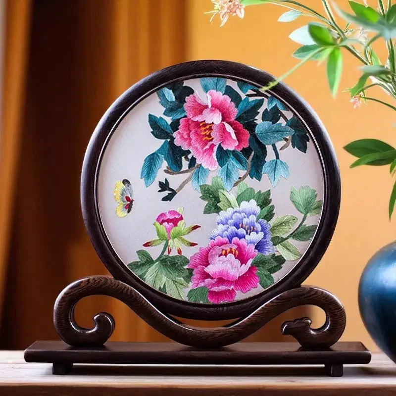 Decorative plate with floral embroidery on a wooden stand against a warm background