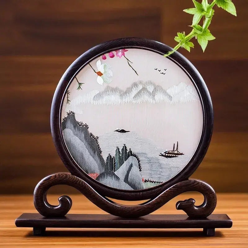 Decorative plate with mountain and boat design on a wooden stand