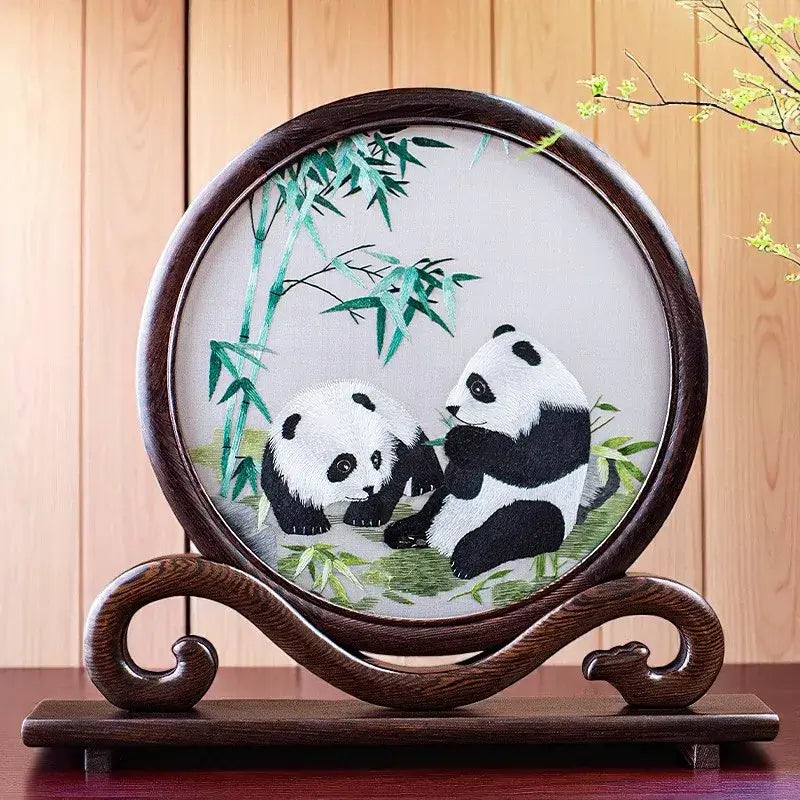 Decorative piece with embroidered pandas on a wooden stand against a wooden background
