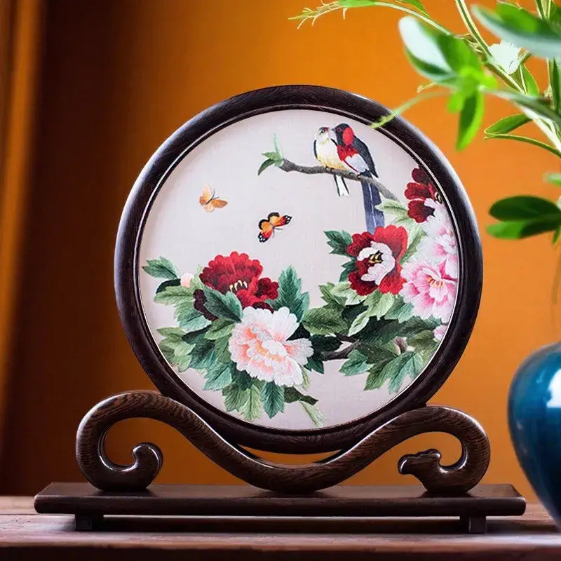 Decorative plate with floral and bird design on a wooden stand against an orange wall.