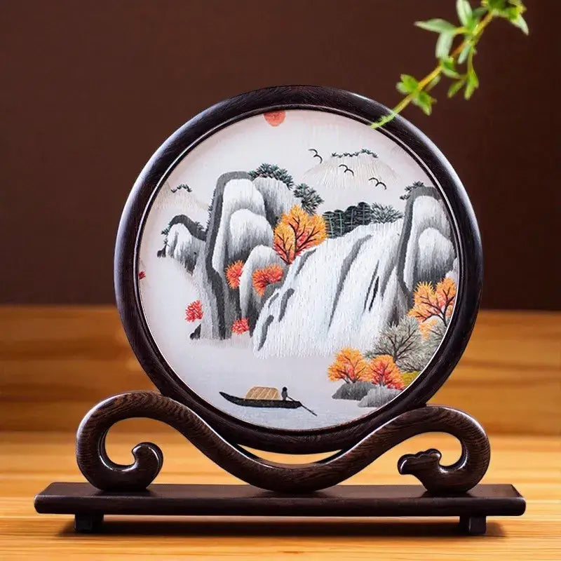 Decorative piece with a mountain and autumn scene on a wooden stand.