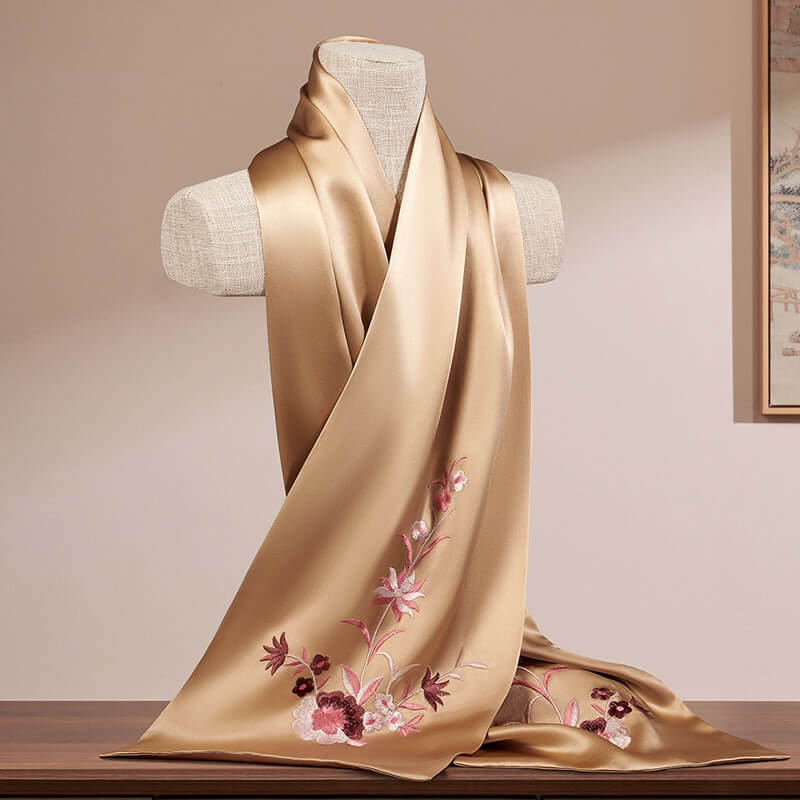 Beige scarf with floral embroidery on a mannequin against a neutral background