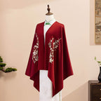 Red embroidered cape on a mannequin against a beige background