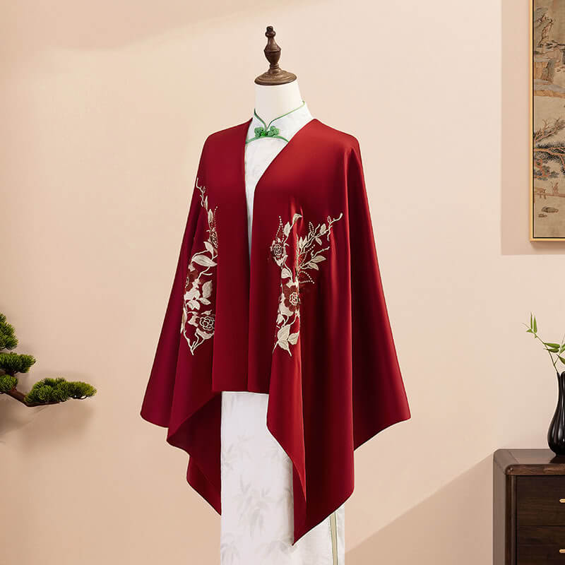 Red embroidered cape on a mannequin against a beige background