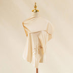 Beige dress on a mannequin with a gold top against a beige background