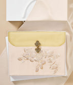 Decorative envelope with floral design and gold clasp on a beige background