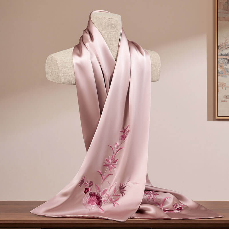 Pink scarf with floral embroidery on a mannequin against a neutral background