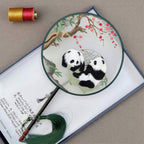 Decorative fan with panda design on a textured surface