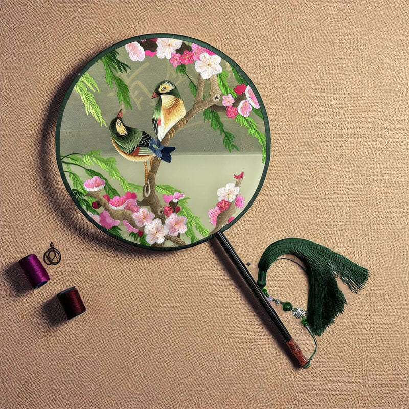 Decorative round fan with birds and flowers on a beige background