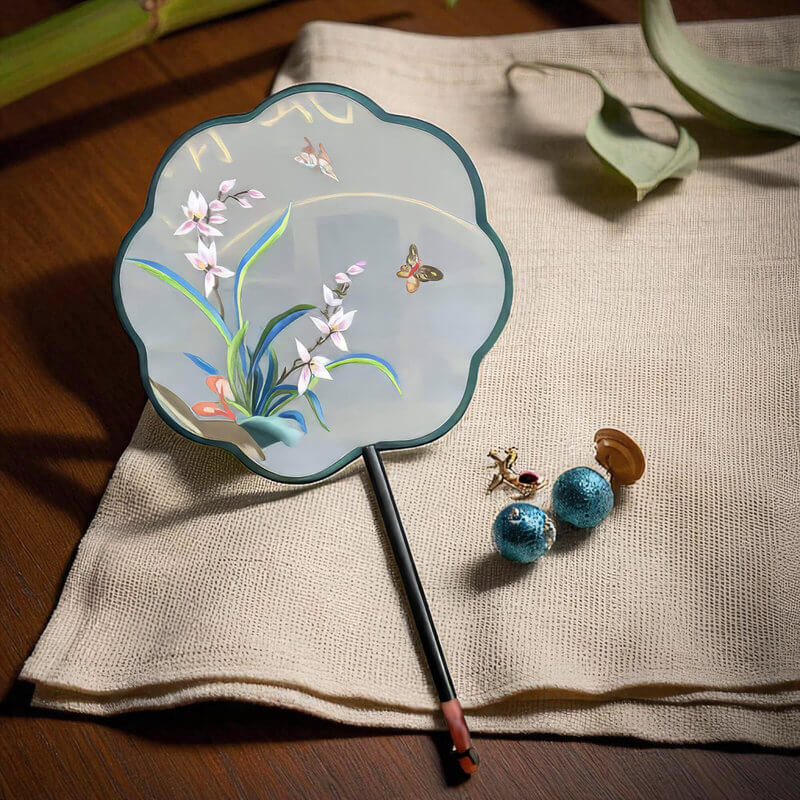Decorative hand fan with floral design on a textured surface