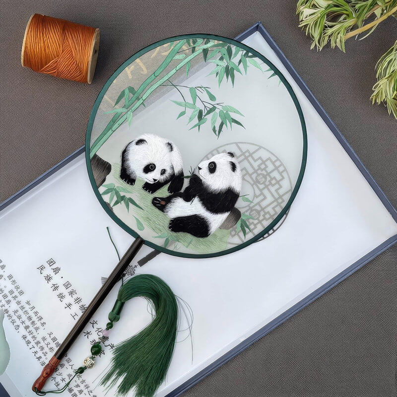 Handheld fan with panda design on a textured surface