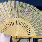 Handheld fan with floral design on gray background
