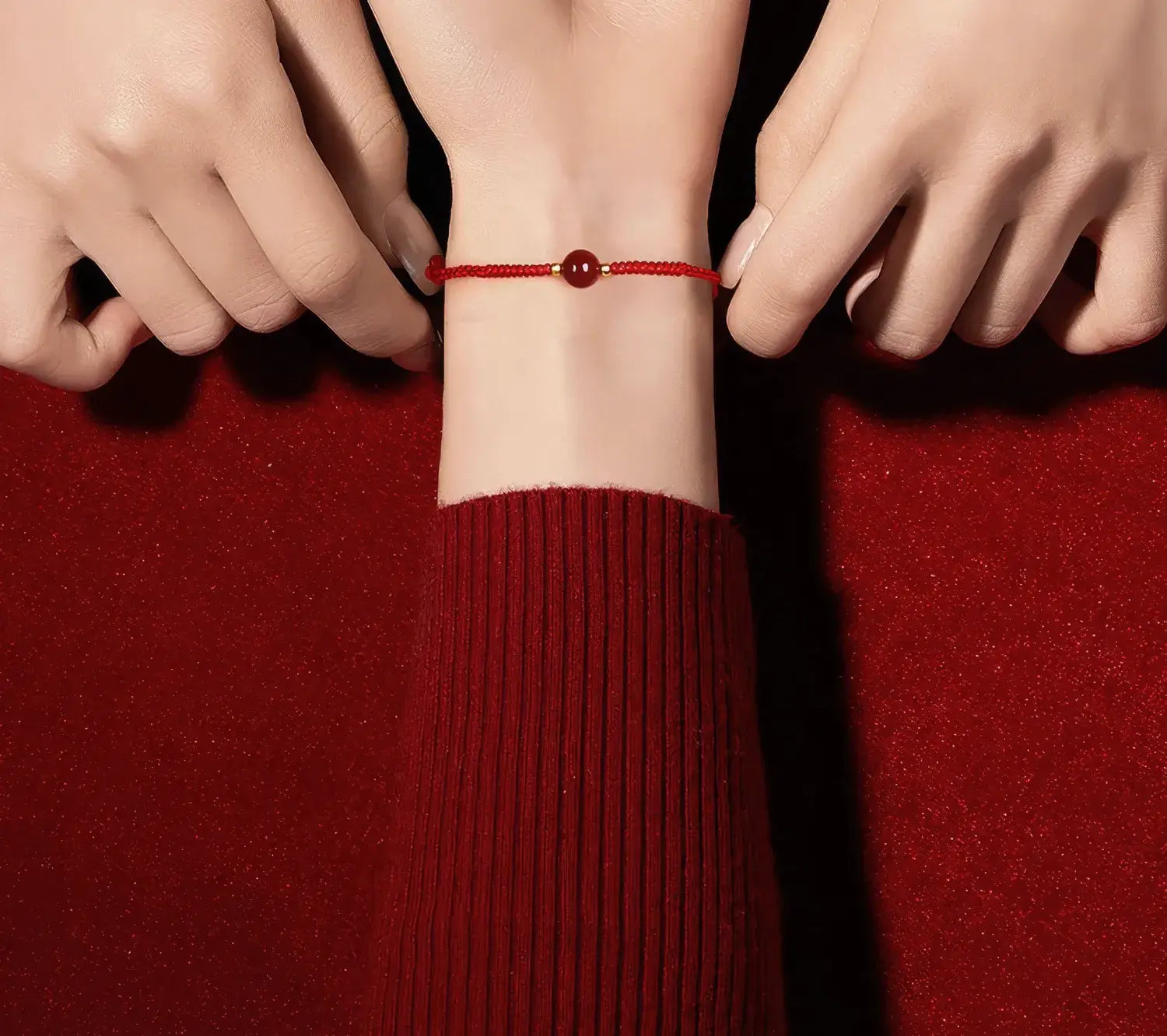 Person wearing a red string bracelet on a red background