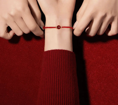 Person wearing a red string bracelet on a red background