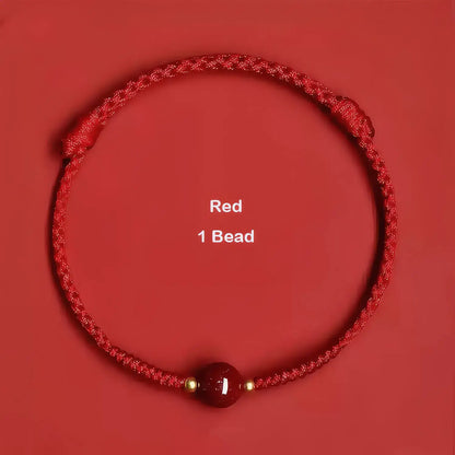 Red braided bracelet with a single red bead on a red background