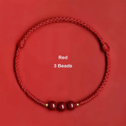 Red cord bracelet with three beads on a red background