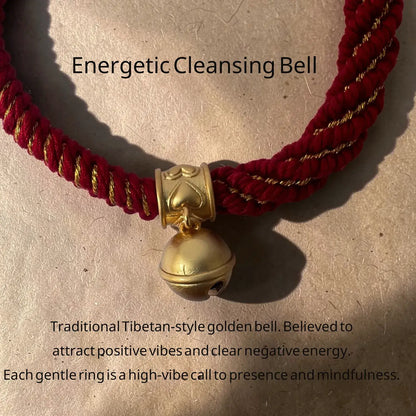 Red and gold rope necklace with a Tibetan-style golden bell on a beige background.