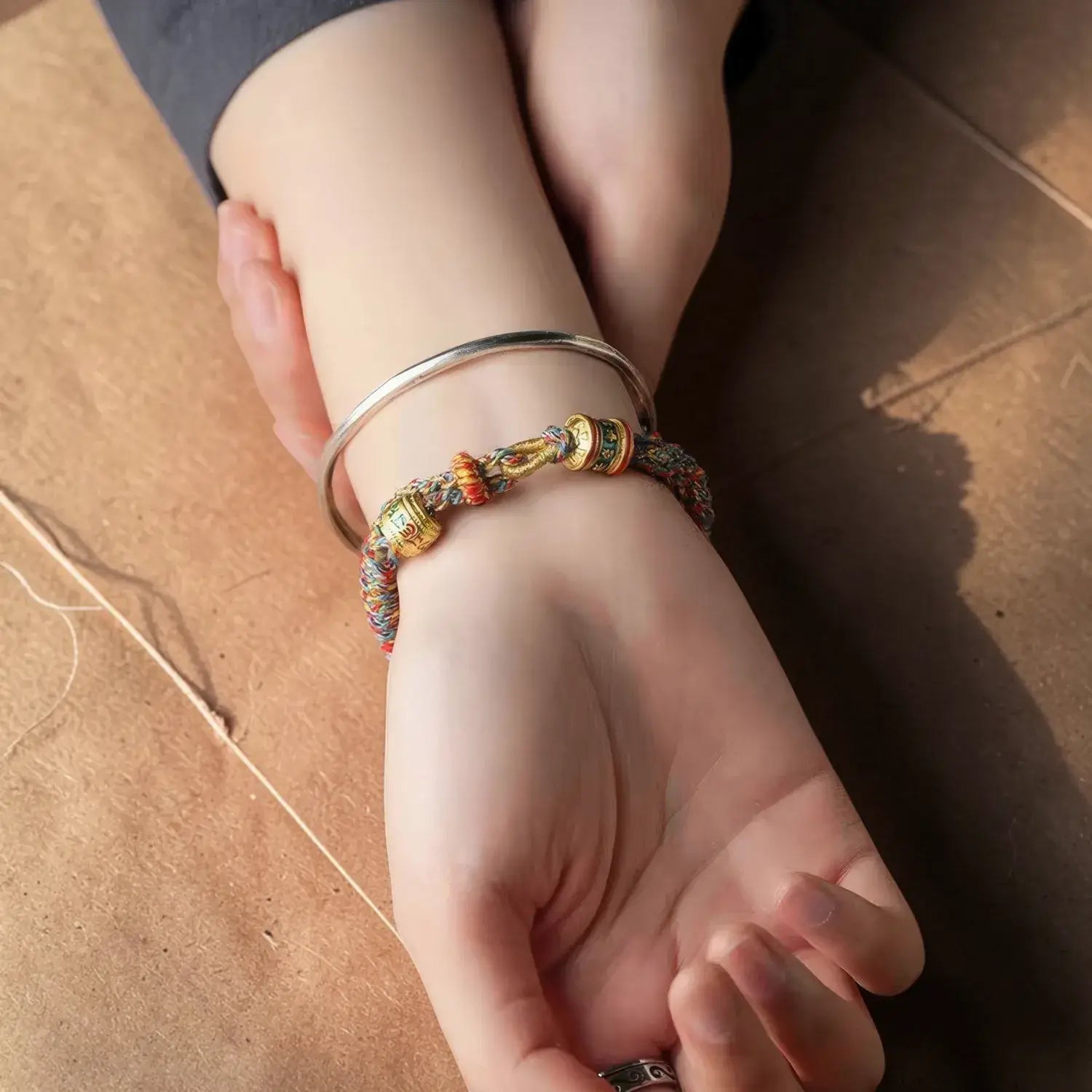 Close-up of a wrist wearing multiple bracelets on a wooden surface