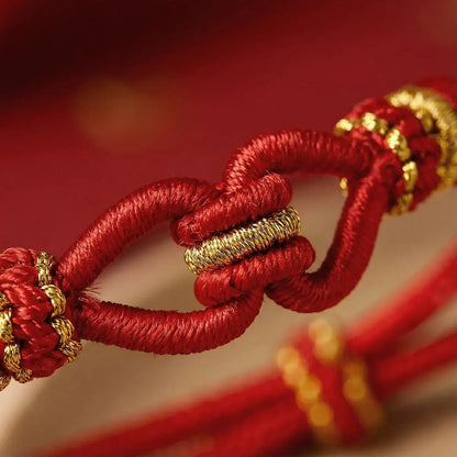 Close-up of a red and gold knotted cord against a blurred red background