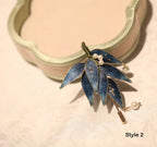 Blue leaf-shaped earring with pearl details on a beige background