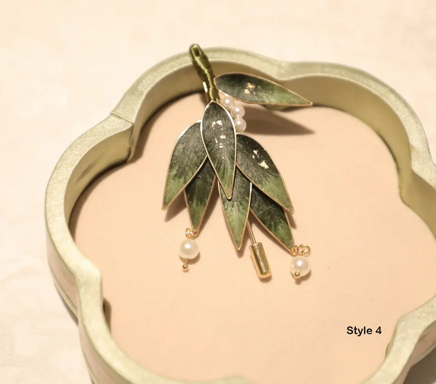 Jewelry with leaf-like design and pearl accents on a beige background
