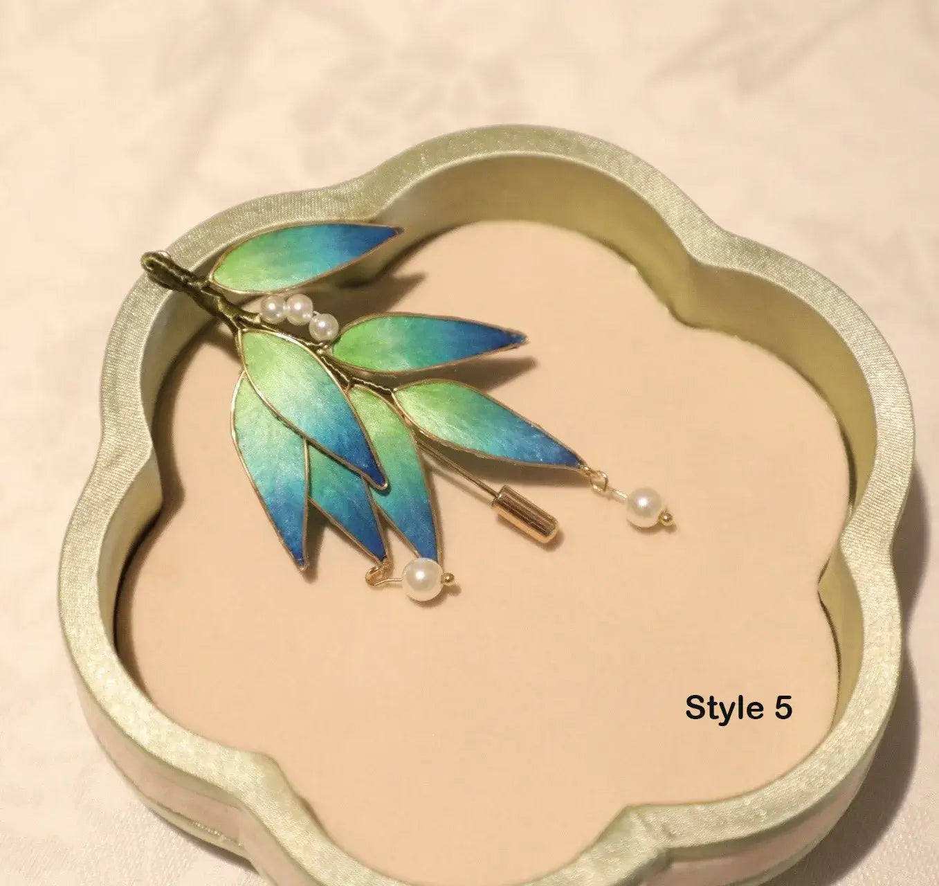 Brooch with leaf design and pearls on a decorative stand
