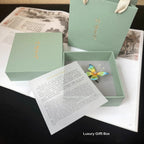 Luxury gift box with a colorful butterfly figurine and a letter on a dark surface.