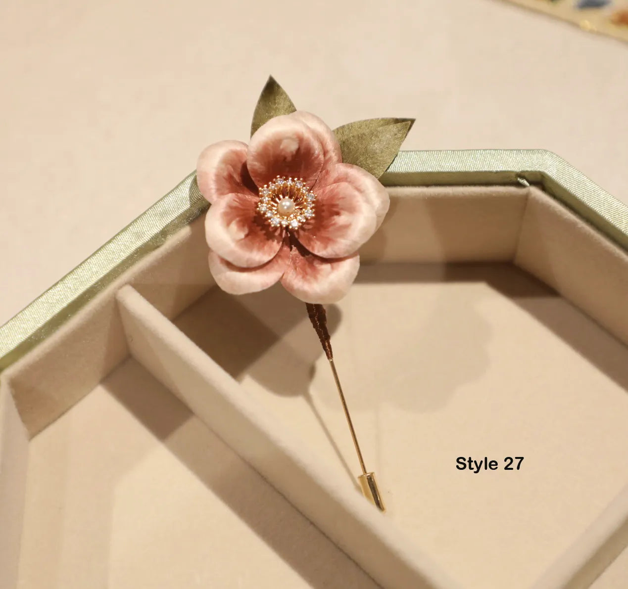Floral brooch with a gold pin on a beige surface
