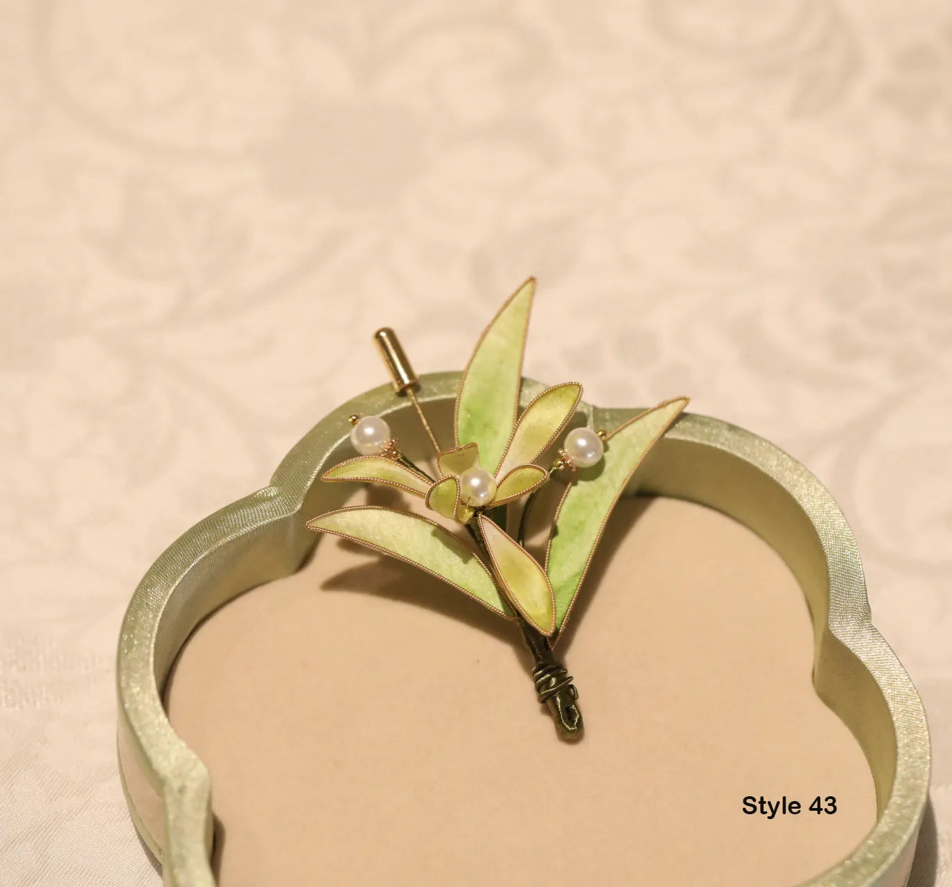 Gold headband with leaf and pearl design on a beige background