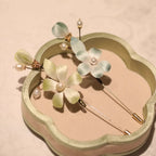 Floral hairpin with green flowers and pearls on a decorative stand.