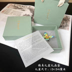 Green gift box with a butterfly figurine and letter on a textured surface