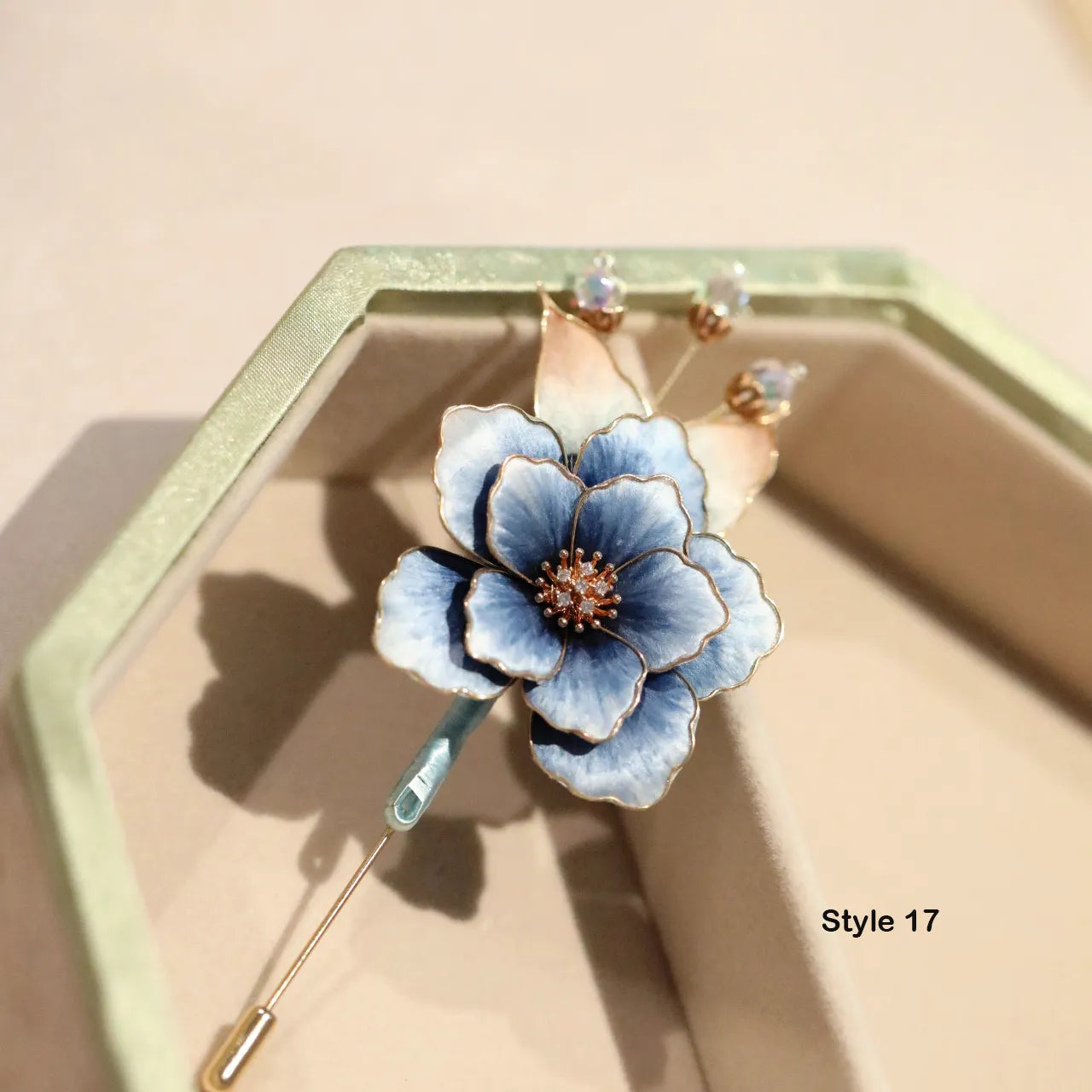 Blue floral brooch with gold accents on a beige background
