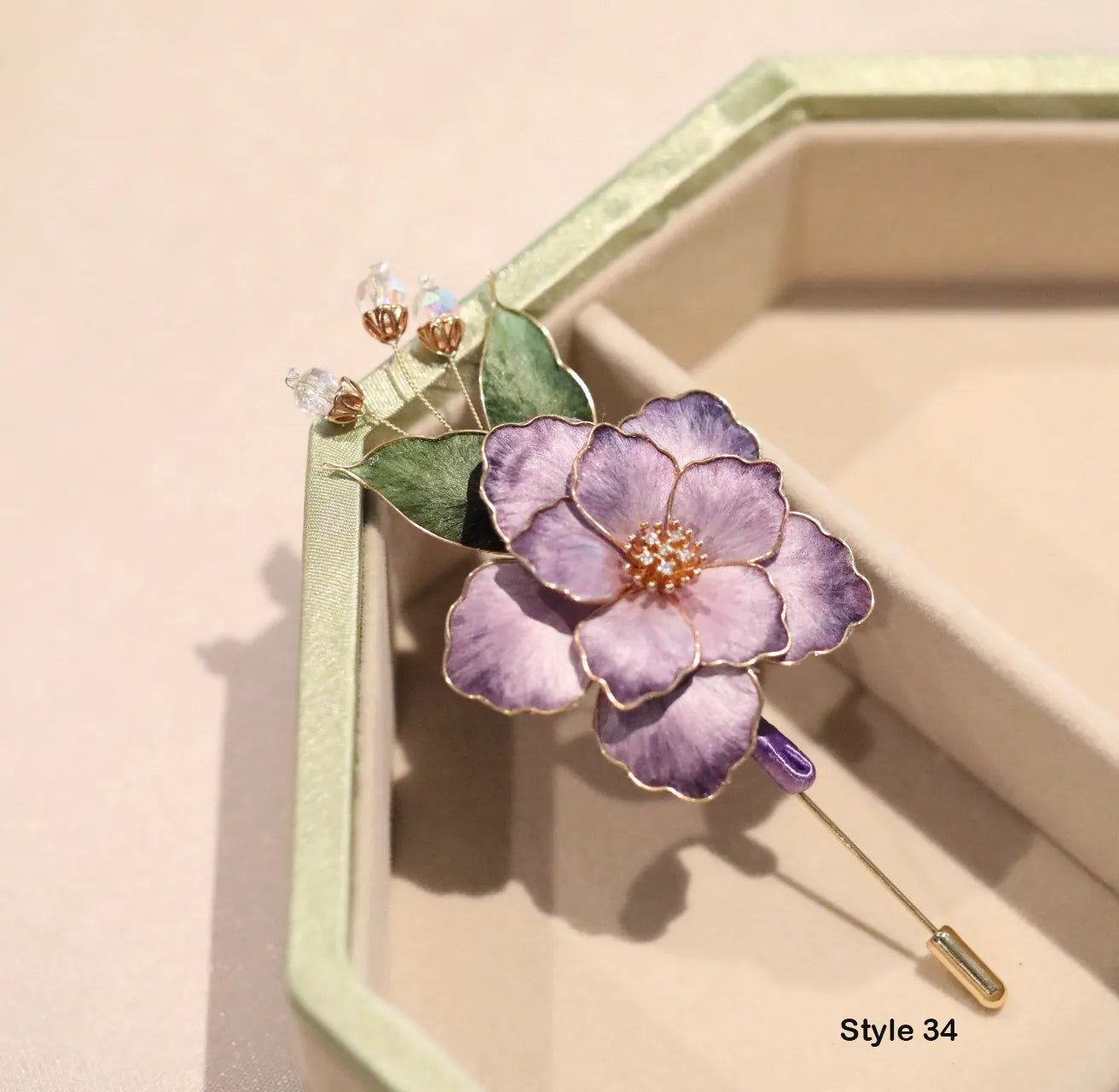 Purple flower-shaped brooch with gold accents on a beige background