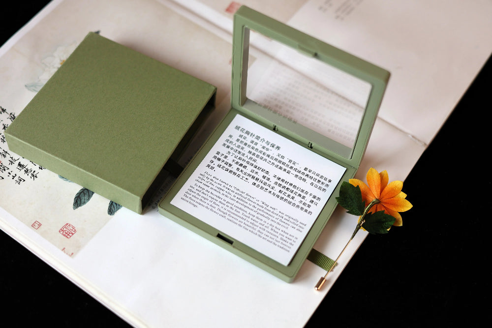 Green jewelry box with a mirror on top, containing text and a flower, placed on a book.