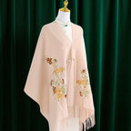 Beige shawl with floral embroidery on a mannequin against a green curtain background