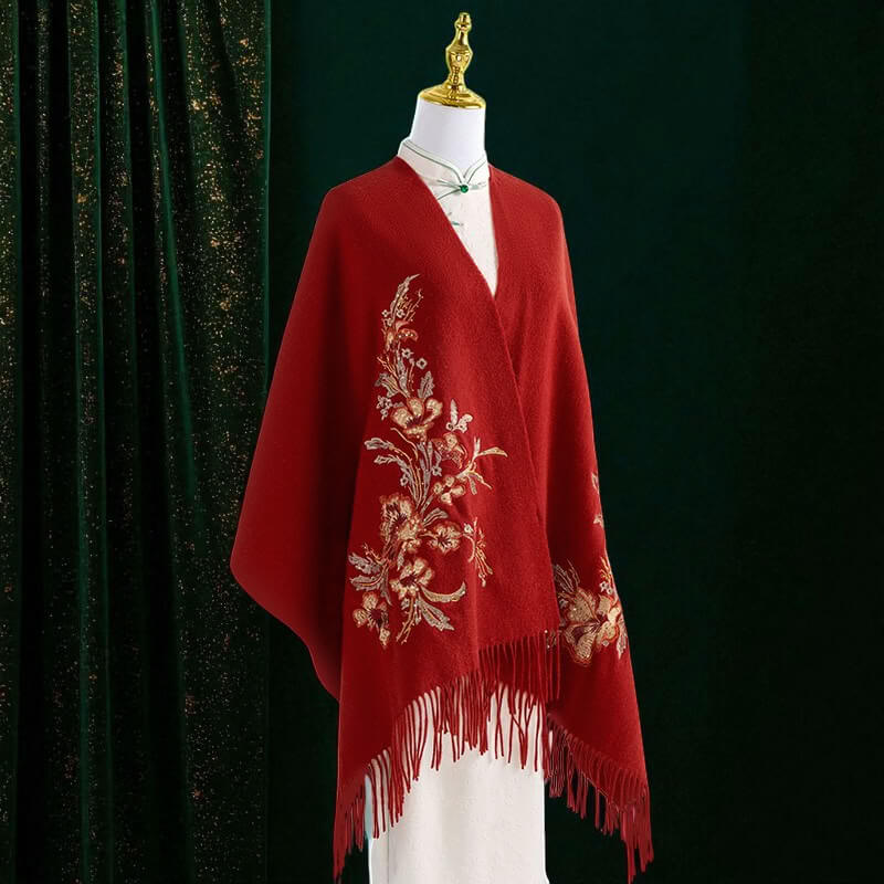 Red embroidered shawl on a mannequin against a dark green curtain background