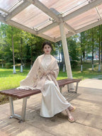 Woman in a traditional outfit sitting on a bench in a park