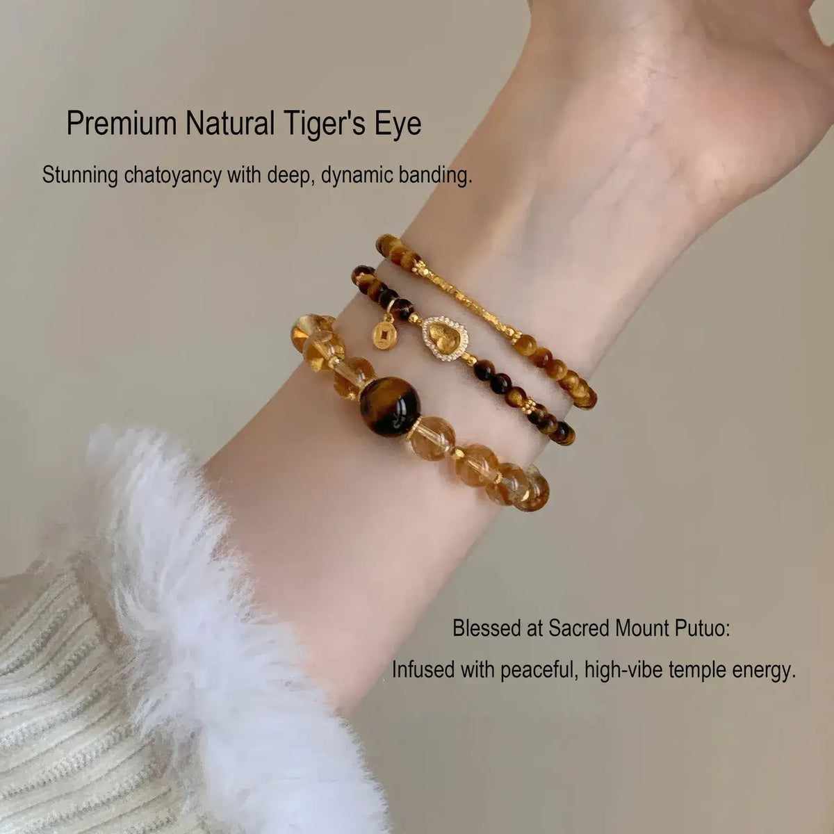Three beaded bracelets displayed on a person's wrist, featuring natural tiger's eye, amber, and gold-toned beads, with decorative charms. The image includes promotional text overlays.