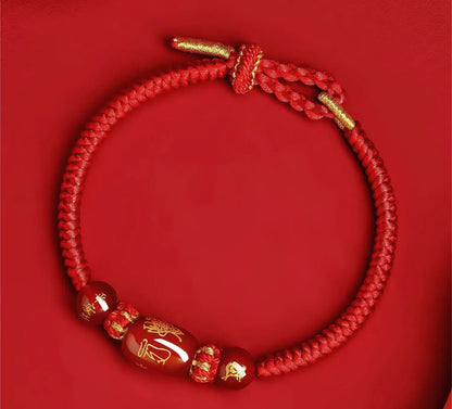 Red braided bracelet with gold accents on a red background