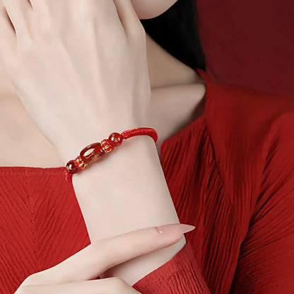 Close-up of a hand wearing a red bracelet with a blurred background