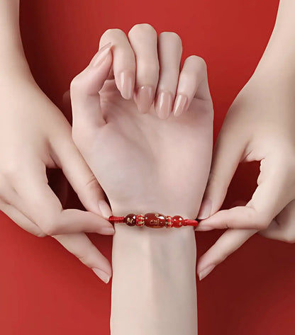 Close-up of a hand wearing a red beaded bracelet against a red background