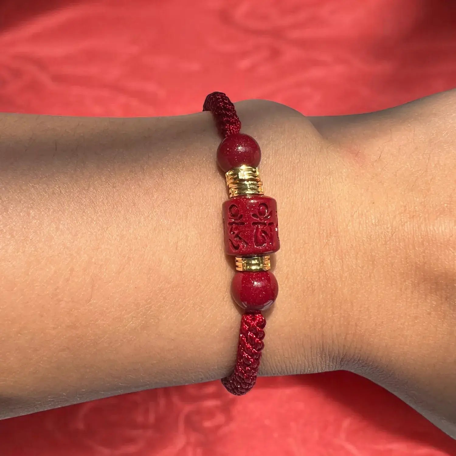 Red bracelet with a gold accent on a wrist against a red background